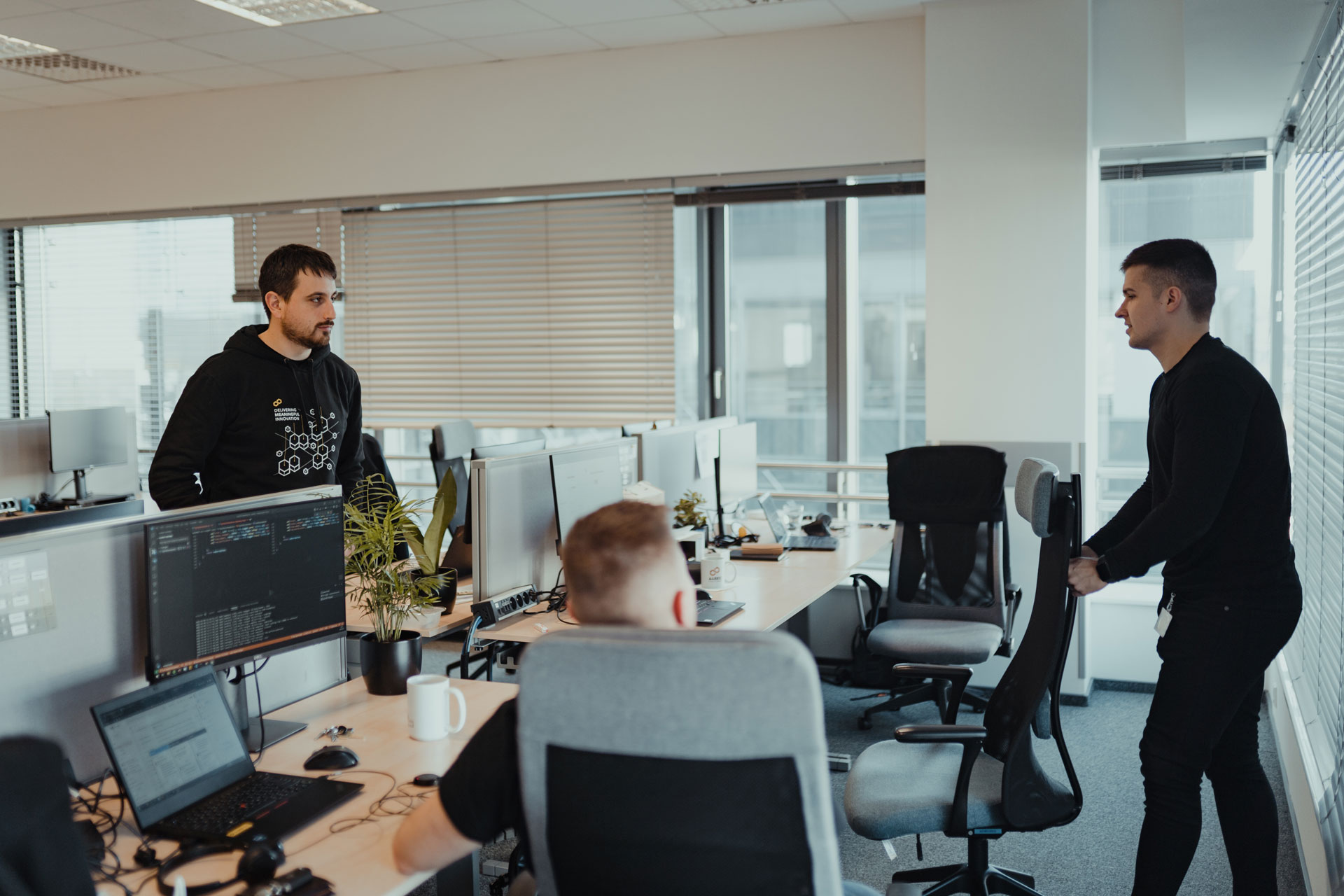 Three people in the office, standing and talking