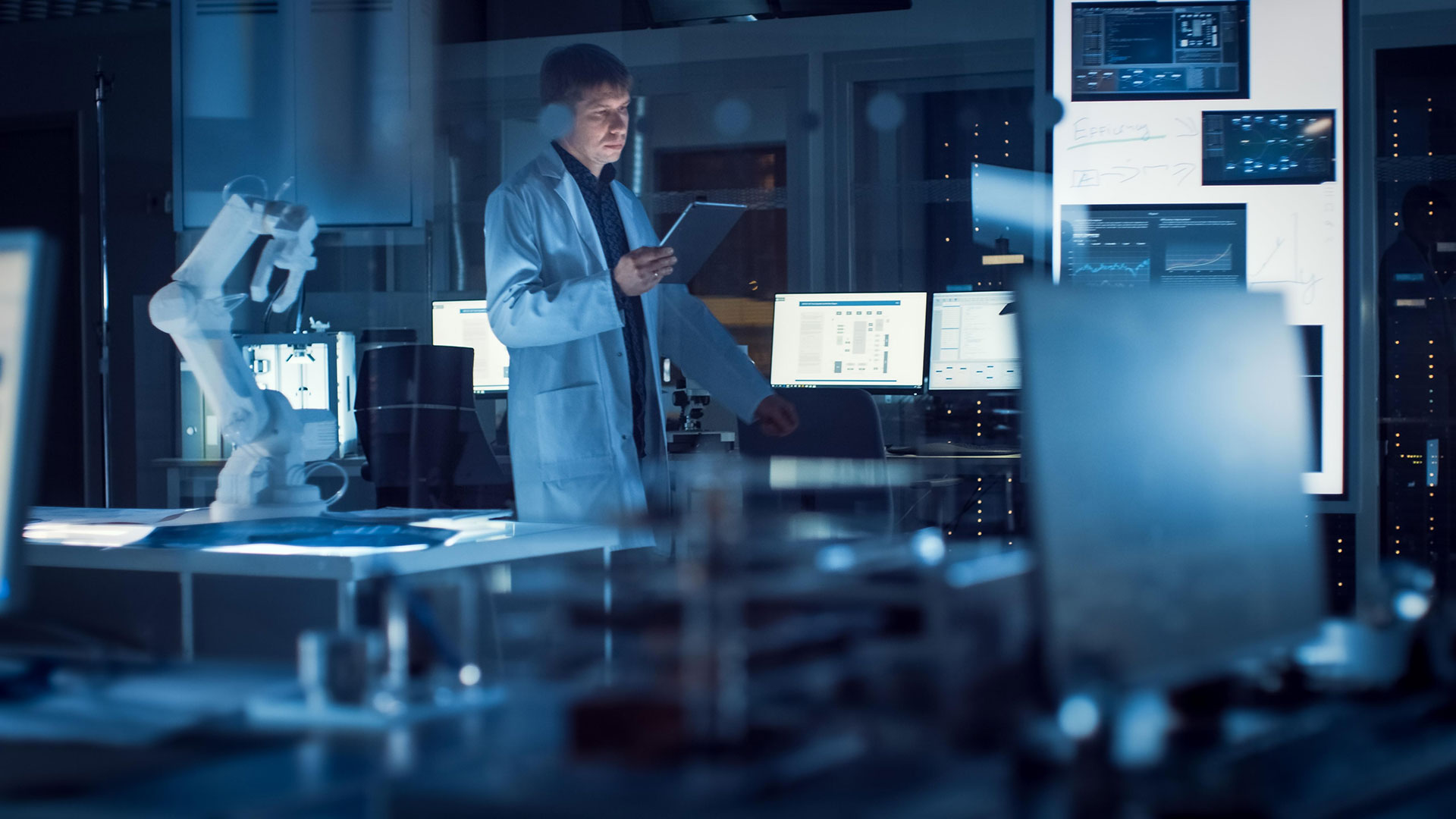 A woman in a a lab with dim light, looking on a tablet in her hand