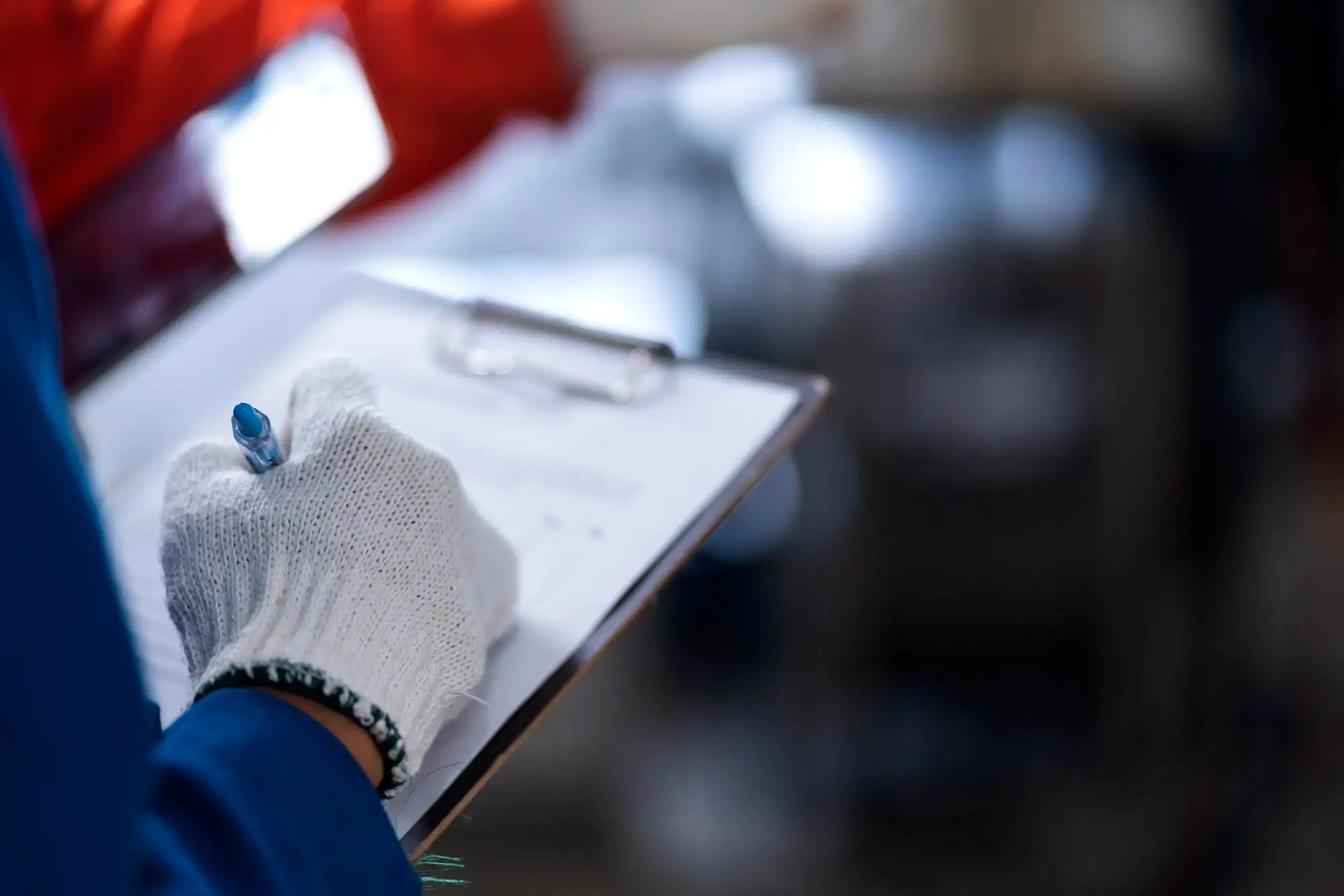 Manufacturing manager holding a clipboard next to disconnected legacy machines representing industrial data silos.